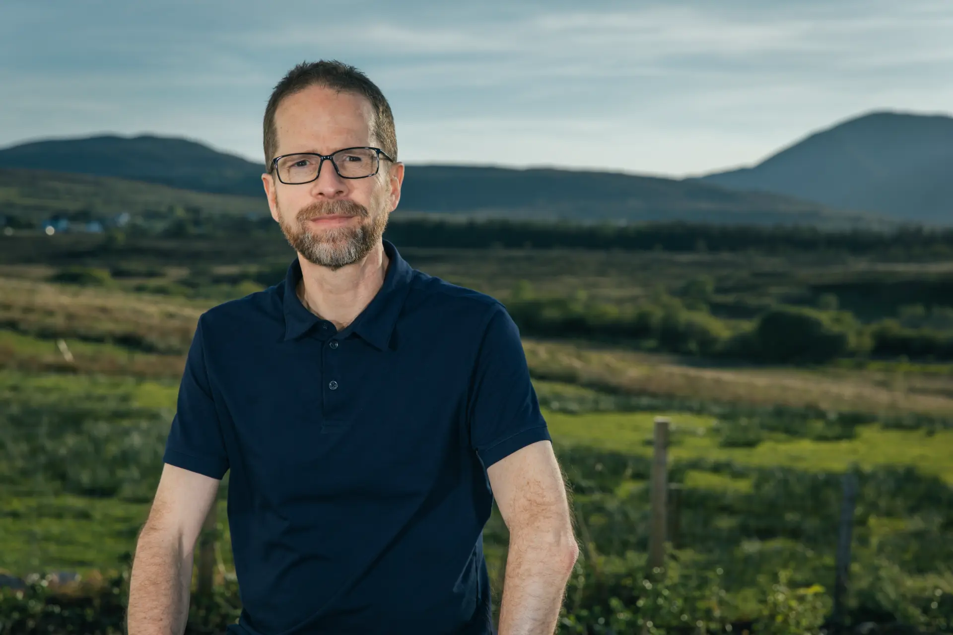 Matthew Savage outdoors on the Isle of Skye, hills behind him