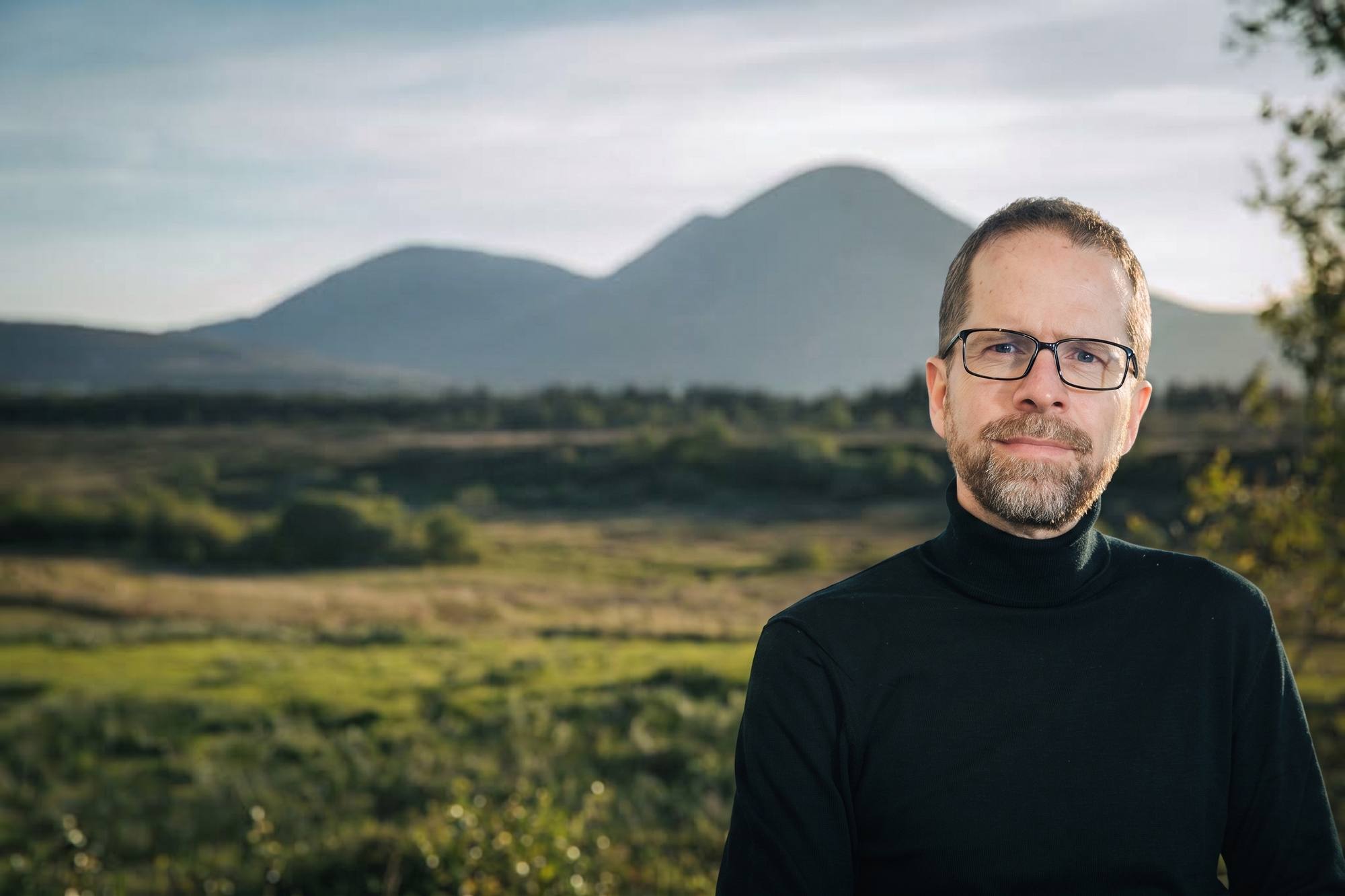 Matthew Savage, photographed outdoors on the Isle of Skye, mountains behind him