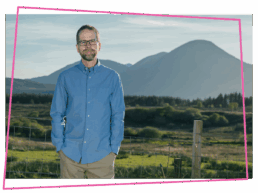 Matthew in a blue shirt stood in front of a mountain